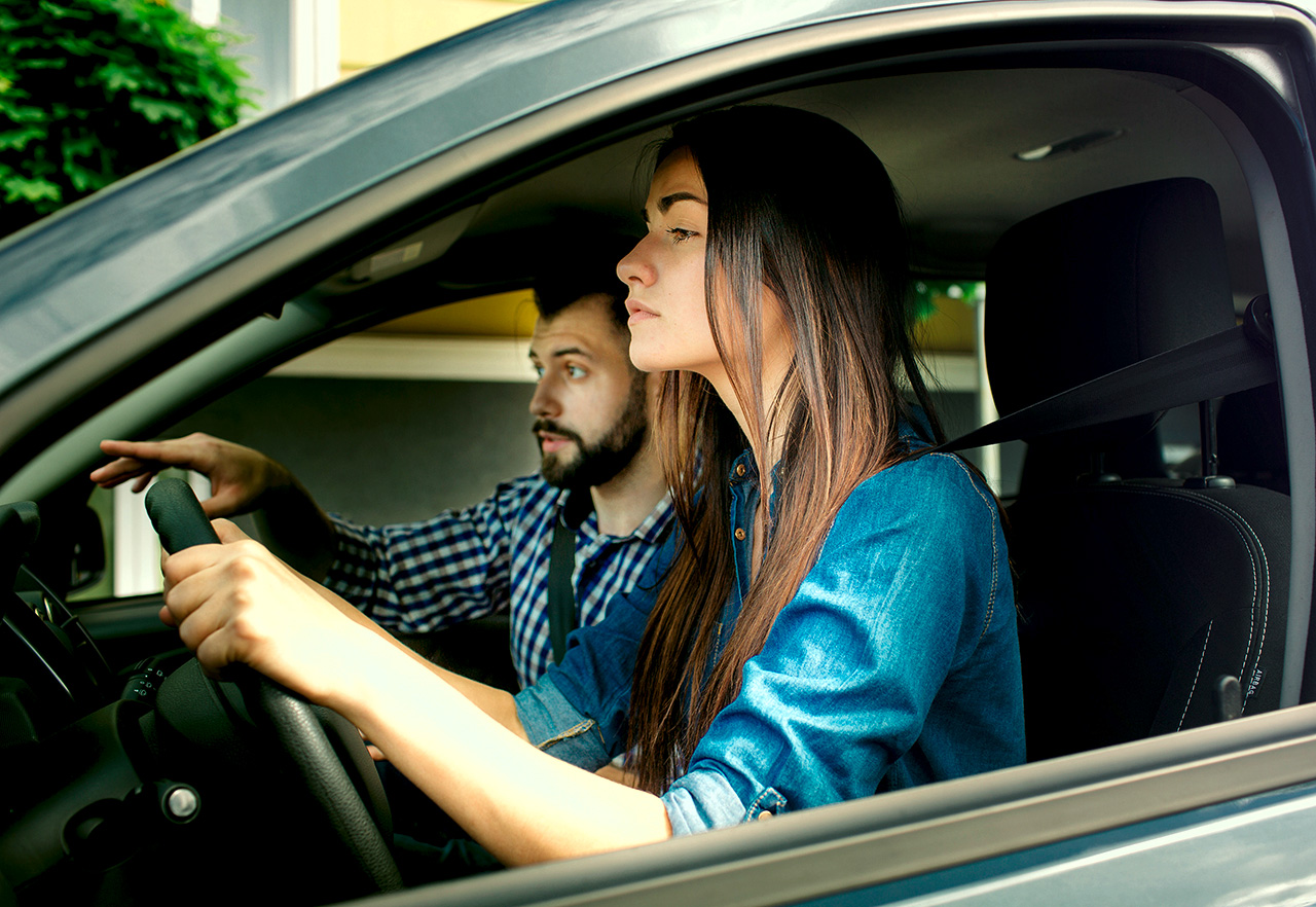 Pärchen sitzt im Auto und parkt entspannt auf einem Parkplatz in der Stadt ein.